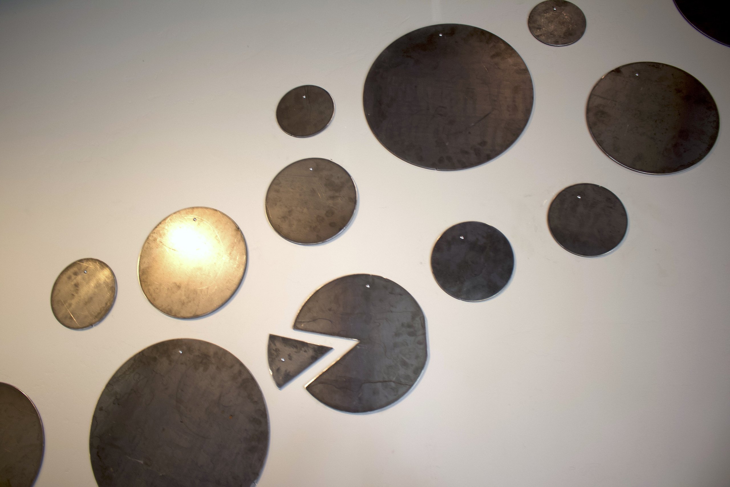 The wall of pizza pans with slice-shaped cutouts, a HomeSlice decor signature