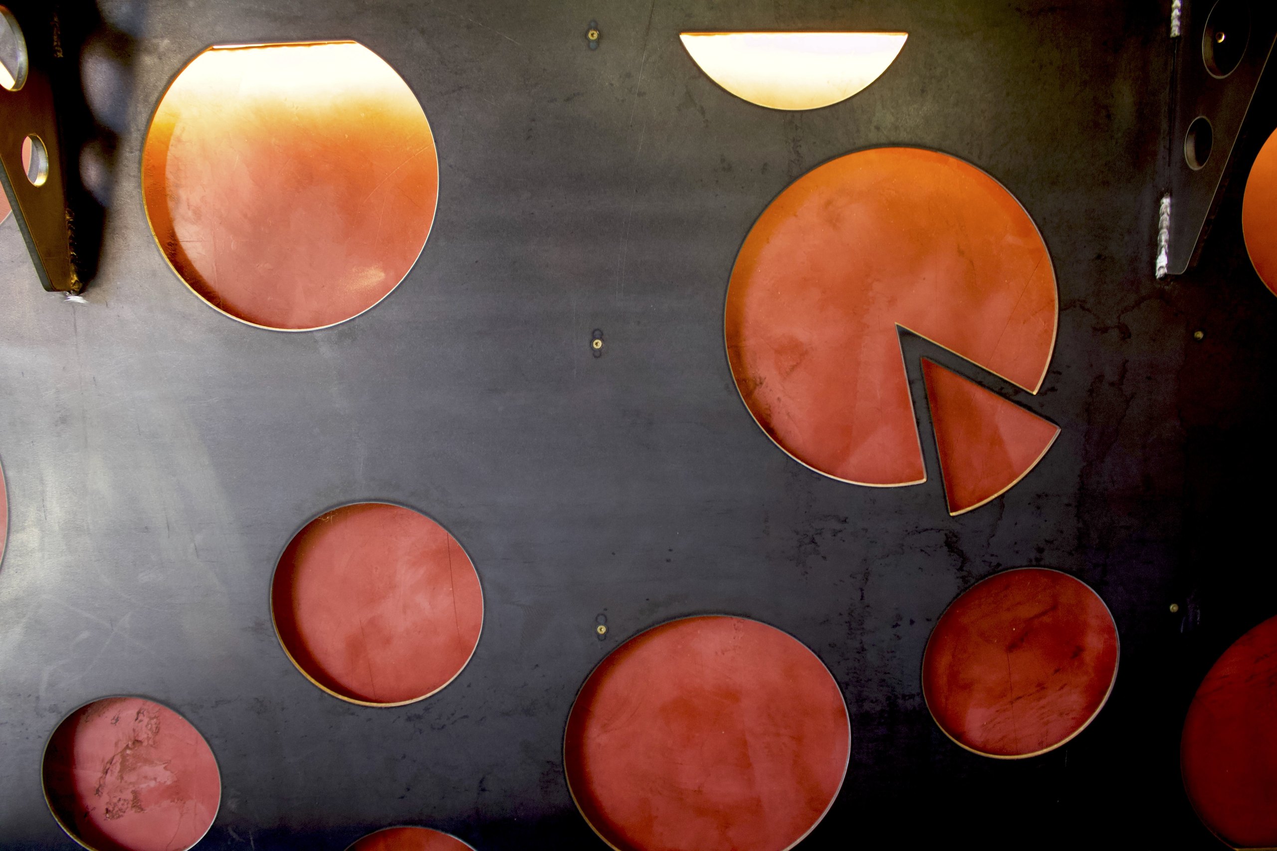 The wall of pizza pans with slice-shaped cutouts, a HomeSlice decor signature