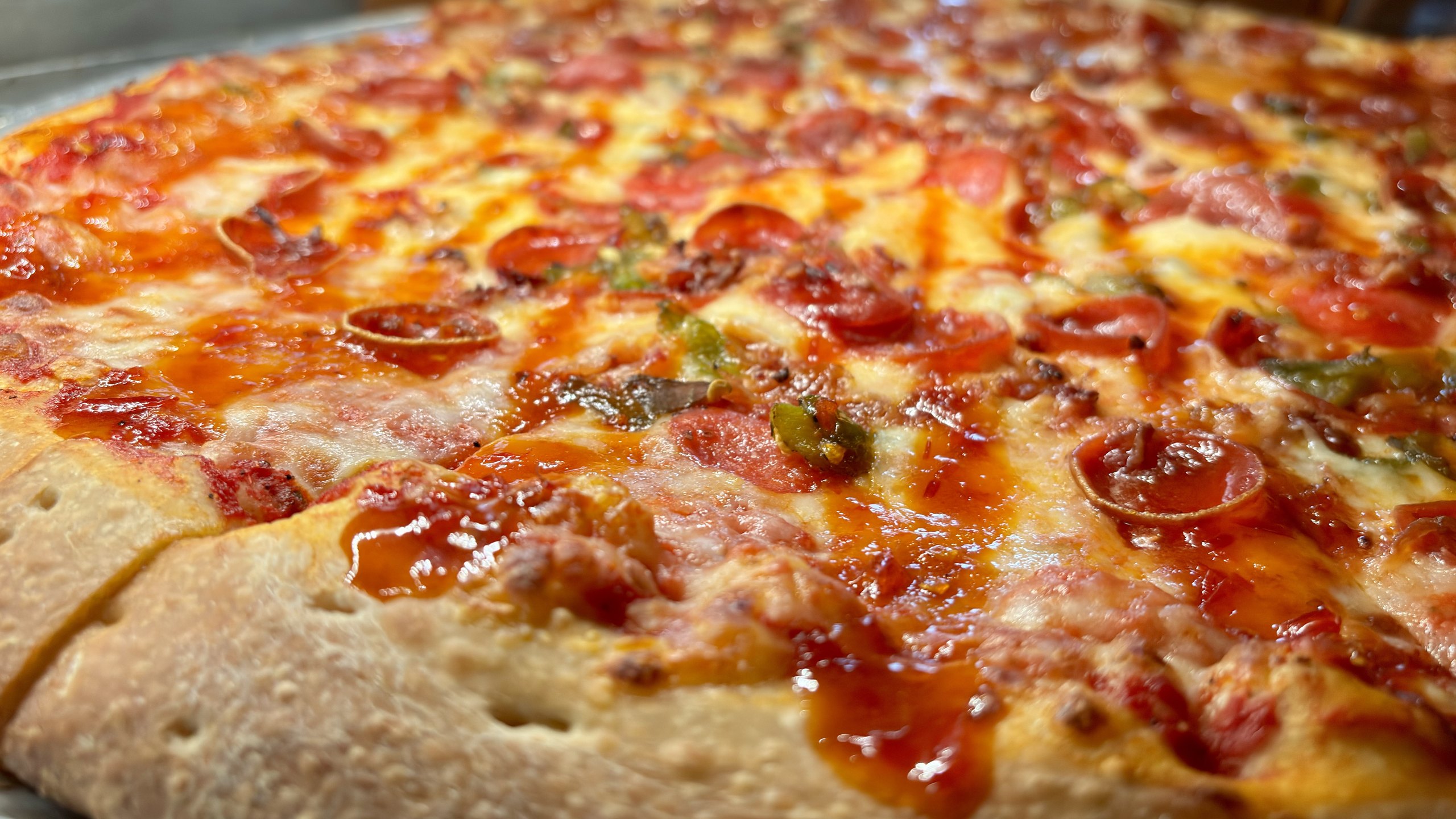 Macro close-up of a HomeSlice pepperoni pizza slice with a glossy hot glaze