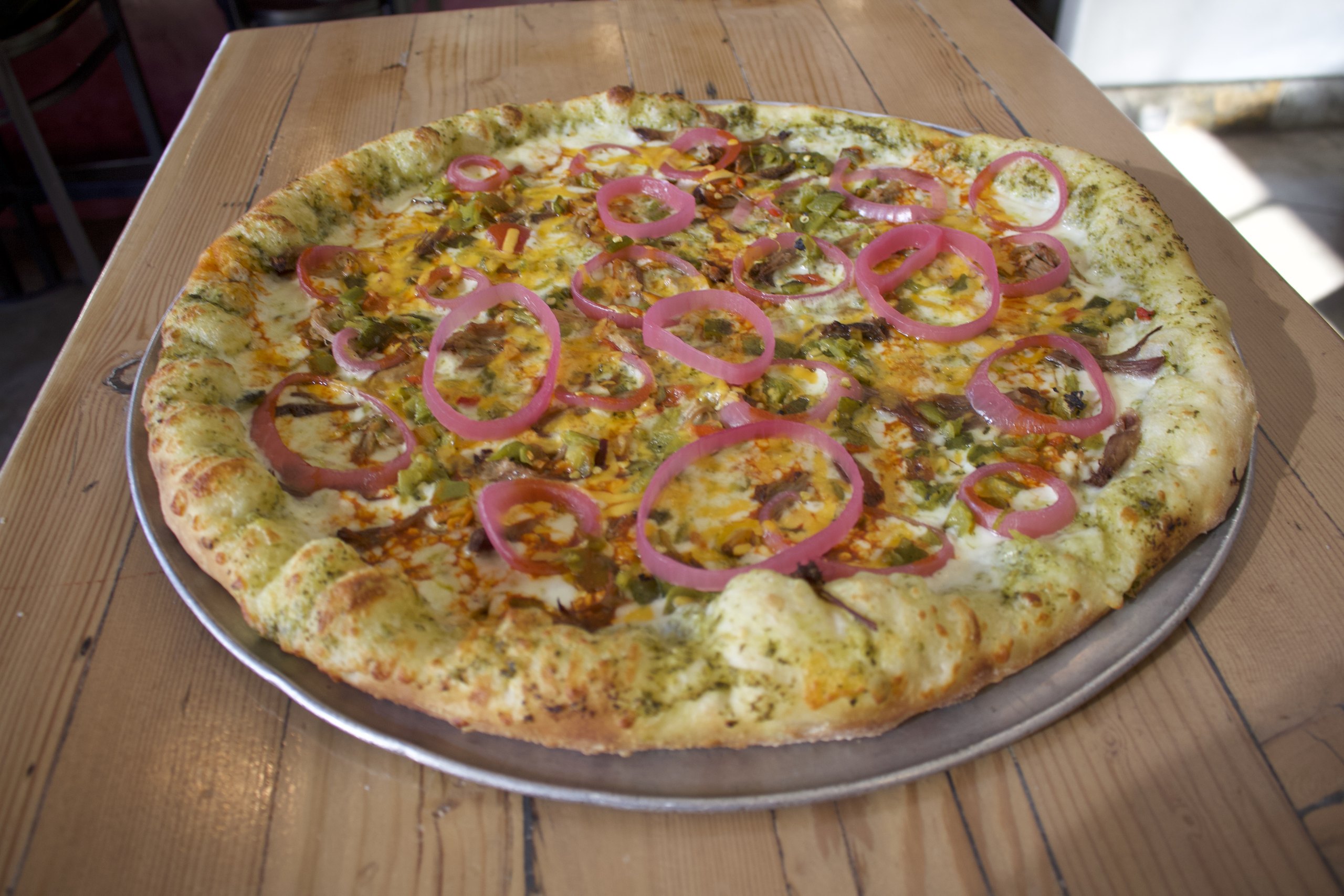 Pizza topped with pickled red onion rings and green chile