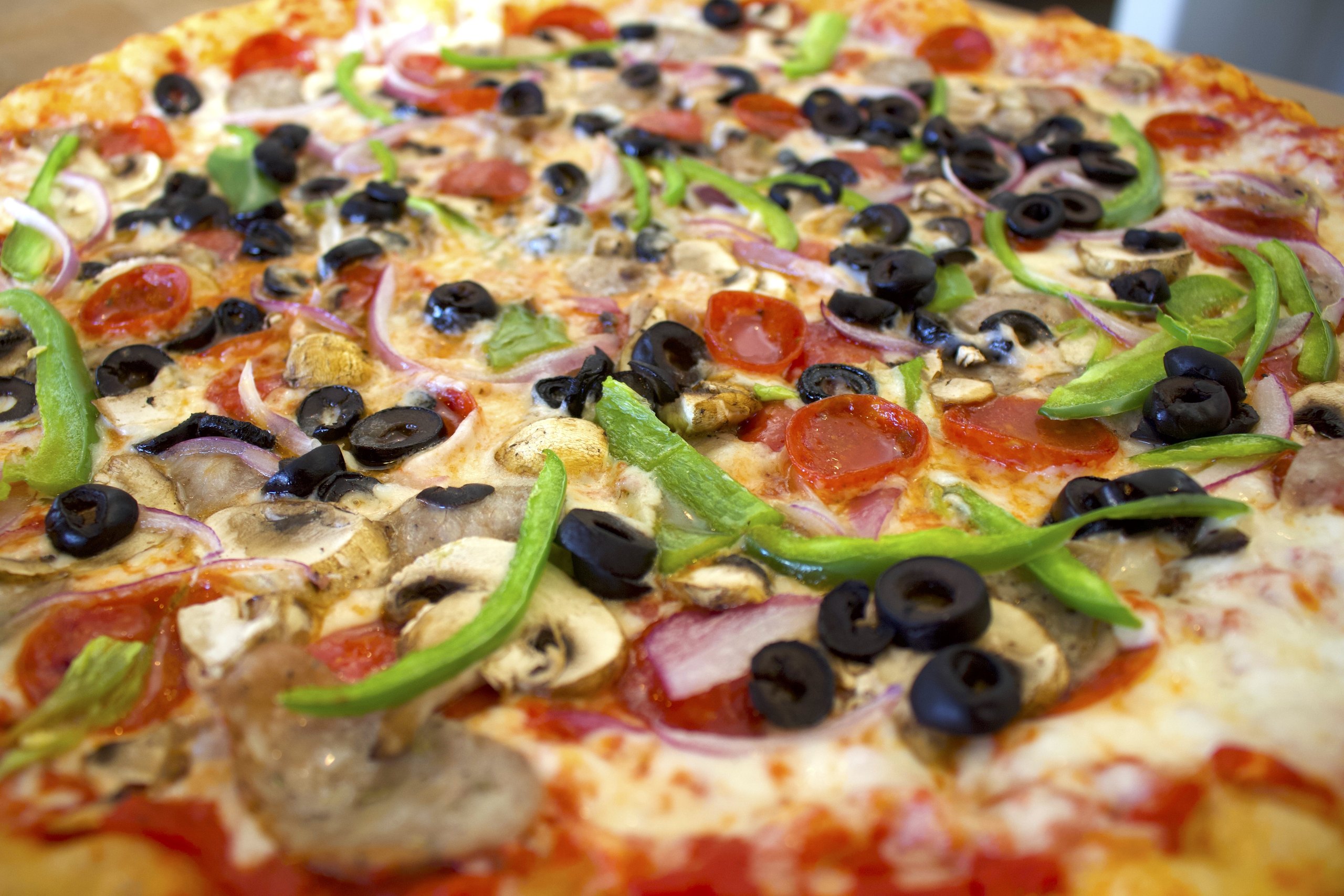 Macro close-up of a loaded supreme-style HomeSlice pizza