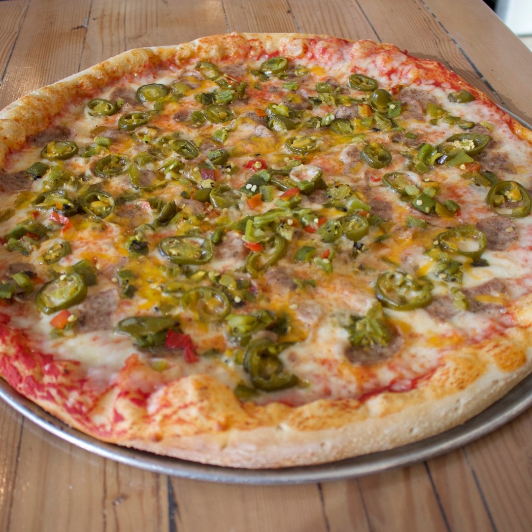Overhead shot of a HomeSlice pie topped with jalapeno and green chile